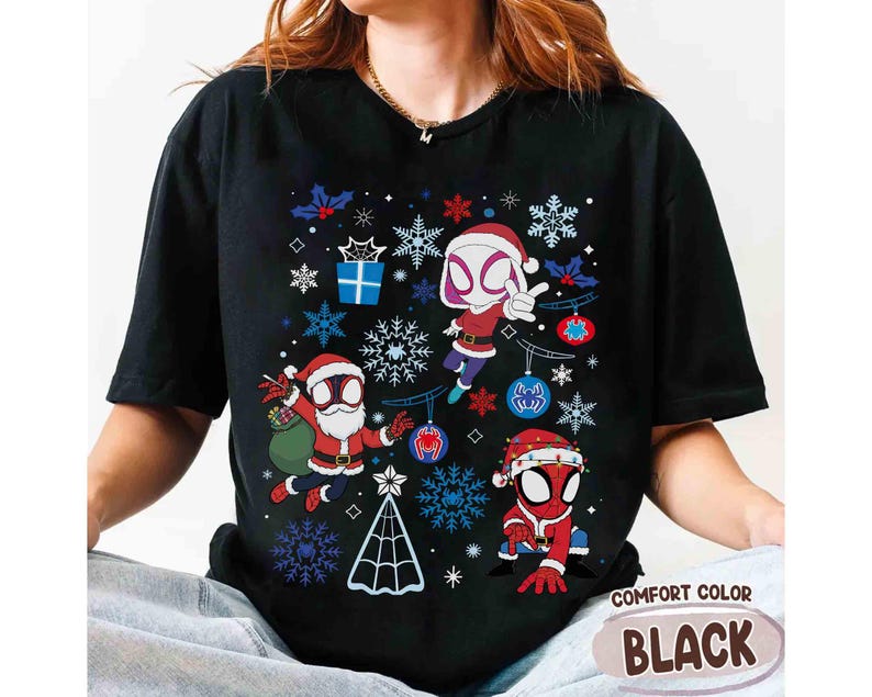 May include: Black Comfort Color t-shirt featuring a Christmas-themed graphic with Spider-Man characters in Santa hats and snowflake designs. The shirt has the words "Comfort Color" and "Black" printed on it.