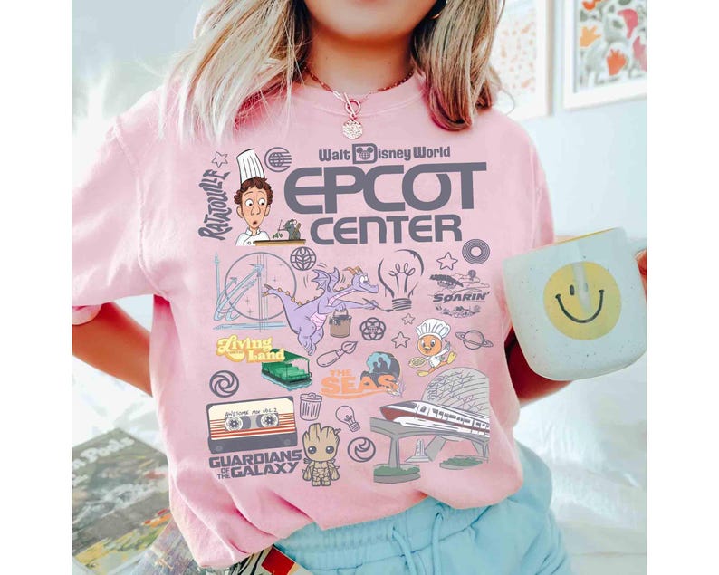 Peut inclure: T-shirt rose clair avec un motif graphique des attractions et personnages d'Epcot Center &agrave; Walt Disney World. Le motif comprend le texte "EPCOT CENTER" et des images de Figment, Remy et les Gardiens de la Galaxie.