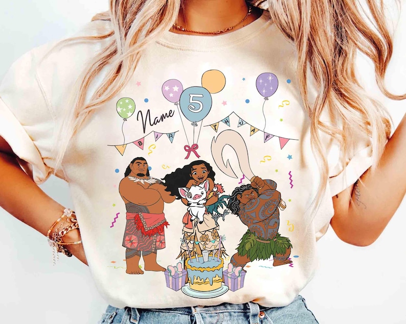 Puede incluir: Camiseta color crema con un gr&aacute;fico colorido de personajes de una popular pel&iacute;cula animada. El dise&ntilde;o incluye una tarta de cumplea&ntilde;os, globos y el n&uacute;mero 5. La palabra "Name" est&aacute; escrita encima del dise&ntilde;o.