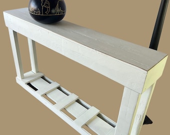 May include: White wooden shelf with a decorative black gourd with gold elephant carvings on top. The shelf has a whitewashed finish and a rustic look.