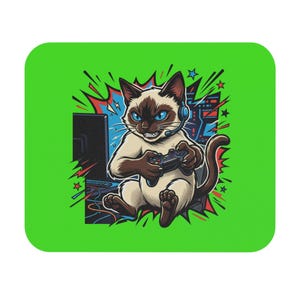May include: A rectangular mouse pad with a bright lime green border featuring a graphic illustration of a Siamese cat wearing a headset and holding a game controller while sitting in front of a computer monitor with colourful comic book style accents.