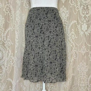 Peut inclure: Une jupe en dentelle florale noire et blanche. La jupe est mi-longue et a une taille ajustée.