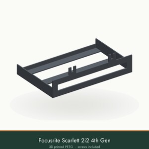 May include: A dark gray 3D printed PETG mounting bracket for a Focusrite Scarlett 2i2 4th Gen audio interface. The rectangular frame features two vertical U-shaped tabs on the front rail and two additional tabs on the rear support structure.
