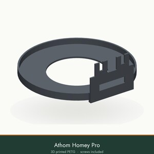 May include: A dark gray circular 3D printed PETG mounting bracket for an Athom Homey Pro device. The mount features a flat ring base with an integrated vertical rectangular attachment point containing a central horizontal cutout. Screws included.