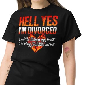 May include: Black t-shirt with the text "HELL YES I'M DIVORCED" in red and white, with a fiery heart graphic. The shirt also includes the text "I said 'In Sickness and Health' I did not say 'In Sadness and Hell' ".