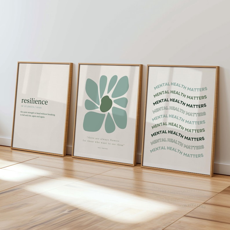 May include: Three framed art prints with wooden frames. The left print has the word "resilience" with a definition. The middle print features a teal abstract flower. The right print says "MENTAL HEALTH MATTERS" in a repeating pattern.