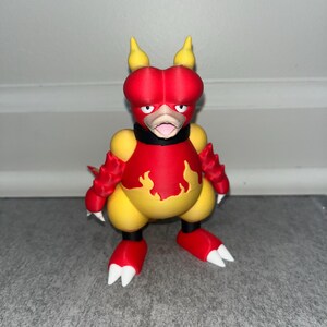 May include: A 3D-printed figurine of a cartoon character with a red head and arms, yellow body, and red feet with white claws. The character has a black collar and a flame design on its chest. The figurine is standing on a gray surface.