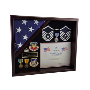 May include: A wooden shadow box display case with a folded American flag, a certificate, medals, and insignia. The certificate reads "The Flag of the United States of America".