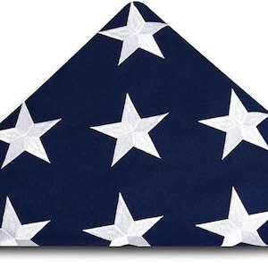 May include: A folded American flag with white stars on a dark blue background. The flag is folded in a triangular shape, with the stars facing outward.