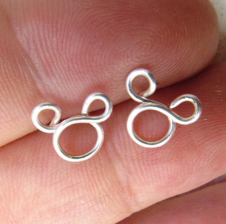 May include: A pair of silver earrings shaped like Mickey Mouse's head.