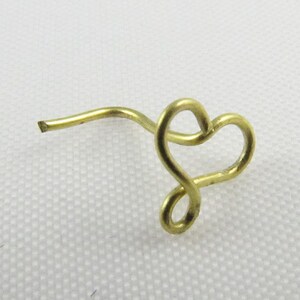 Pu&ograve; includere: Un anello per il naso dorato a forma di cuore con uno stelo curvo.