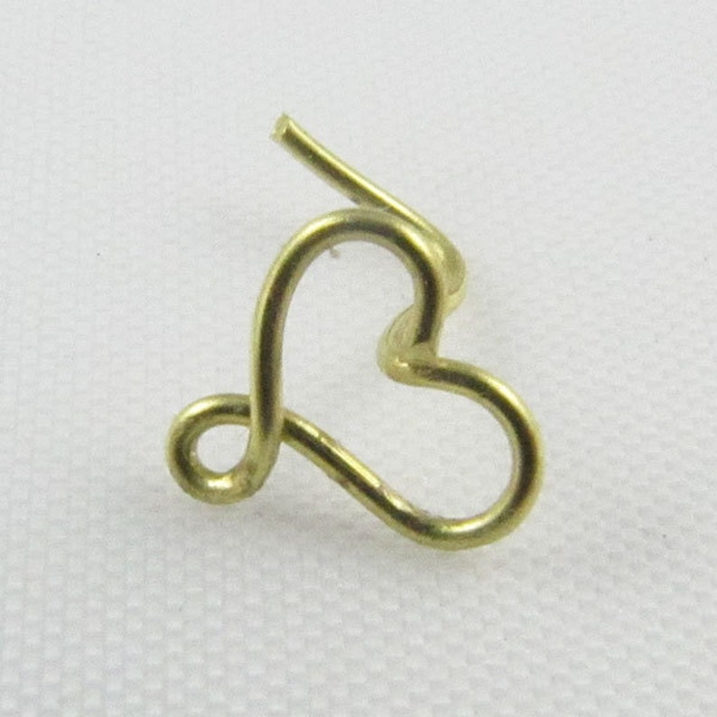 Pu&ograve; includere: Un anello per il naso a forma di cuore in oro, fatto di filo.