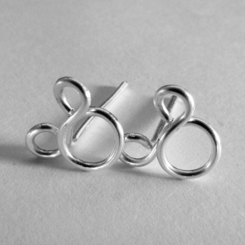May include: A pair of silver earrings shaped like the number eight. The earrings are made of wire and have a simple, modern design.