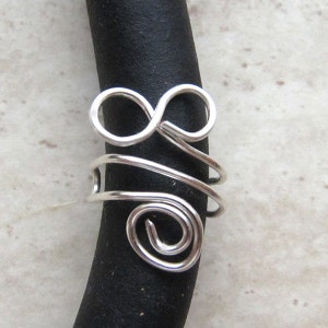 May include: Silver wire infinity symbol charm with a spiral design. The charm is attached to a black stethoscope.