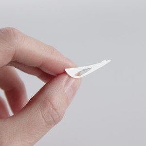 May include: A white adhesive bandage with a small, clear, plastic strip in the center.