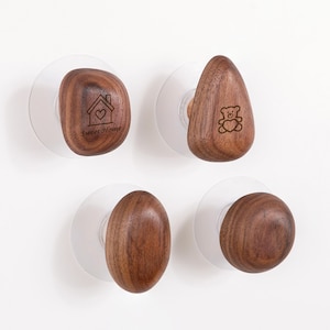 May include: Four wooden cabinet knobs with clear suction cups. Two knobs have engraved designs: a house with a heart and a teddy bear. The other two knobs are oval and round. The text "Sweet Home" is on one knob.