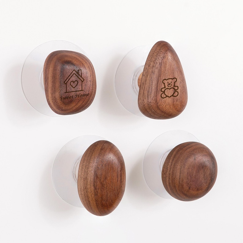 May include: Four wooden cabinet knobs with clear suction cups. Two knobs have engraved designs: a house with a heart and a teddy bear. The other two knobs are oval and round. The text "Sweet Home" is on one knob.
