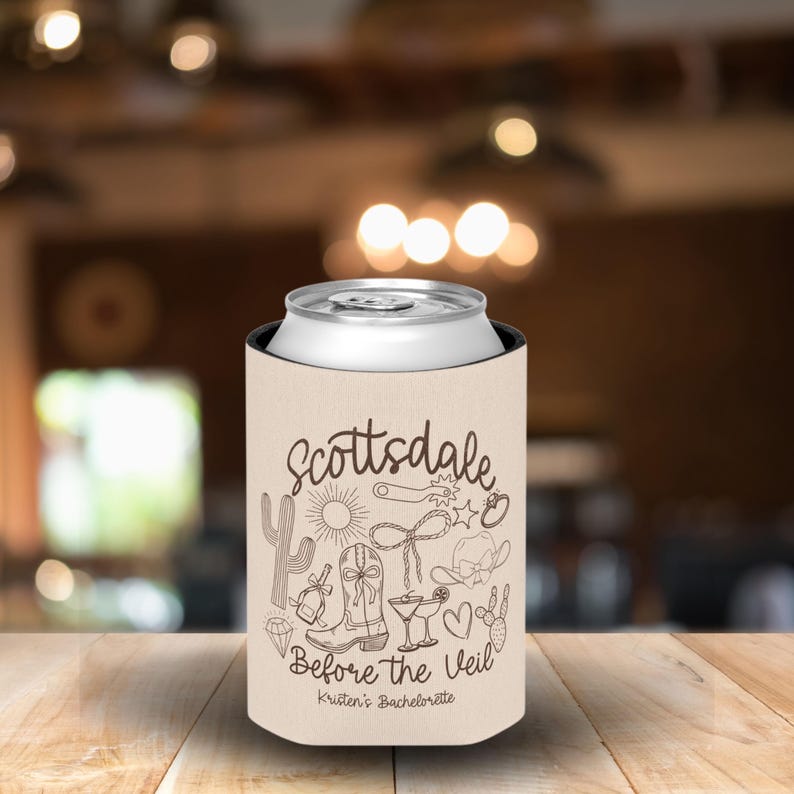 May include: A beige can cooler with the word "Scottsdale" in a script font, along with various desert-themed illustrations. The text "Before the Veil" and "Kristen's Bachelorette" are also printed on the cooler.