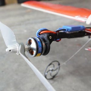 May include: Close-up of a small, silver electric motor with a black propeller attached to a black arm. The motor has a blue label that reads "Power 400" and "Original Brushless Motor".