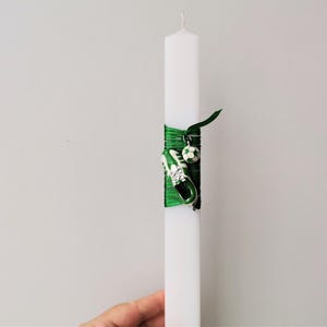 May include: White candle with a green ribbon and a charm of a soccer shoe and ball.