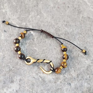 May include: A black cord bracelet with tiger's eye and hematite beads and a gold hook clasp.