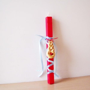 May include: A red Easter candle with a braided dough decoration and blue ribbon accents.