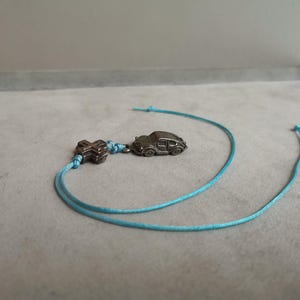 New car charm, silver coloured alloy charm of car and cross on light blue cord, good luck car charm