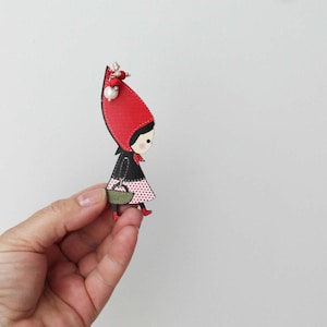 Red riding hood brooch, wooden brooch of red riding hood in profile with long, red hood, black vest and basket in hand, teens beaded brooch
