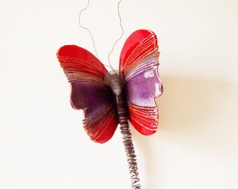 May include: A red and purple ceramic butterfly wall sculpture with a wire tail.