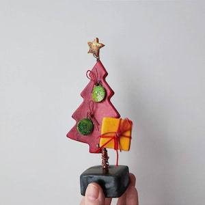Red chistmas tree sculpture, xmas fir tree with green balls and sparkling star on top, ceramic green christmas tree miniature on brown base