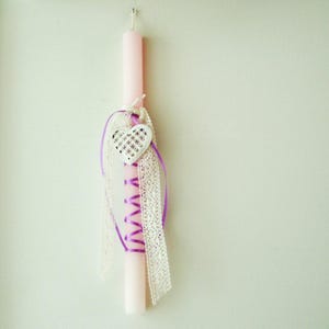 May include: A pink candle with a white heart-shaped charm and purple ribbon and lace accents.