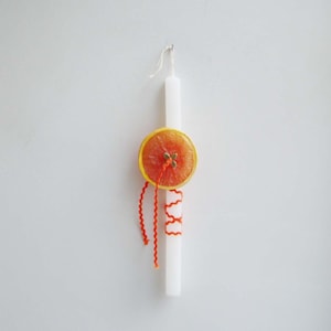 May include: A white candle with a dried orange slice and orange ribbon decoration.
