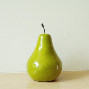 Puede incluir: Un objeto decorativo en forma de pera de cerámica verde brillante.