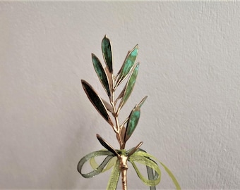 May include: A gold-colored olive branch with green leaves, tied with a green and black ribbon. The branch is a decorative piece.