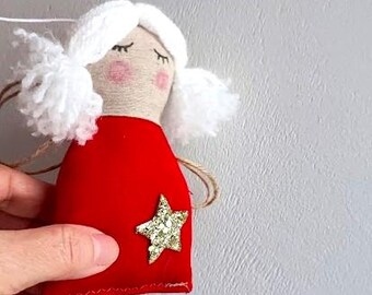 May include: A handmade felt angel ornament with white yarn hair, a red dress, and a gold glitter star.