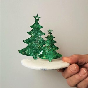 Two chistmas trees, two wooden xmas trees on stone, big and small christmas trees, green sparkling christmas trees set on tumbled stone