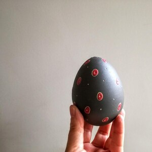 Peut inclure: Un œuf noir avec des pois rouges et blancs.