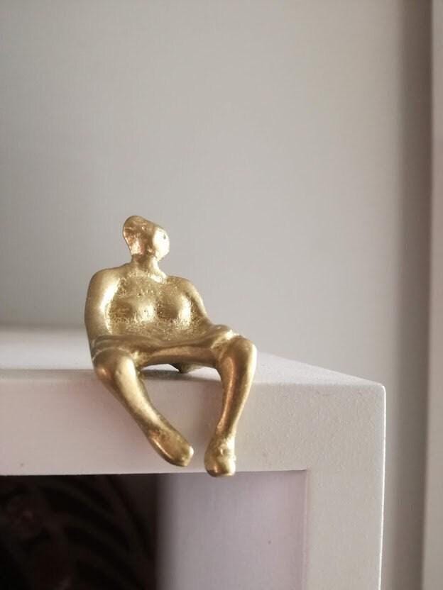 座っている女性の像、座っている女性の真鍮彫刻、棚の端に腰掛けられた
