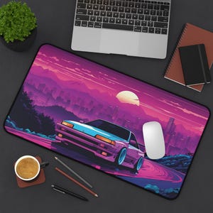 Puede incluir: Una alfombrilla de escritorio de estilo retro de color morado y rosa con un horizonte de ciudad y una puesta de sol en el fondo. Un coche azul y blanco está conduciendo por una carretera en primer plano. La alfombrilla está diseñada para usarse con un ratón de ordenador.