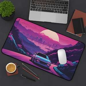 May include: A pink and purple retro-style mousepad with a cityscape and a blue car driving on a winding road. The mousepad has a white computer mouse on it.