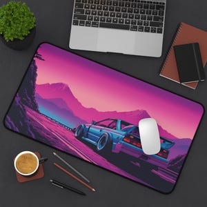 May include: A blue car driving on a road with a pink and purple sunset in the background. The car is a classic sports car with a spoiler and large wheels. The road is lined with trees and mountains in the distance.