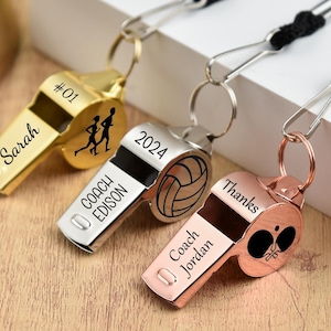 May include: Three personalized metal whistles in gold, silver, and rose gold. The gold whistle has "Sarah" and "#01" engraved, with a running figure. The silver whistle has "Coach Edison" and "2024" with a volleyball graphic. The rose gold whistle says "Coach Jordan" and "Thanks".