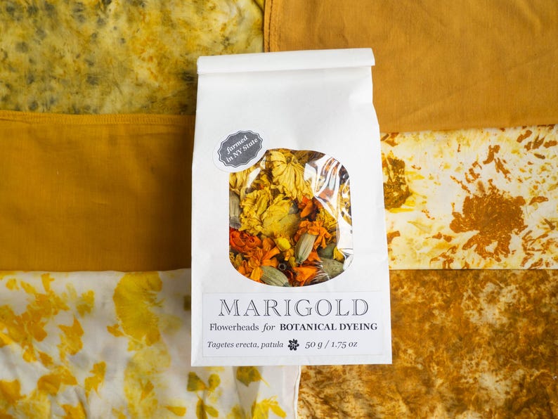 May include: A white paper bag containing dried marigold flowerheads for botanical dyeing, labeled with the text MARIGOLD Flowerheads for BOTANICAL DYEING Tagetes erecta, patula 50 g / 1.75 oz and a sticker stating farmed in NY State.