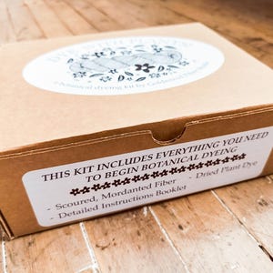 May include: A brown cardboard box for a botanical dyeing kit. The top label reads DYE WITH PLANTS! botanical dyeing kit by Goldenrod Fiber Studio. The front label reads THIS KIT INCLUDES EVERYTHING YOU NEED TO BEGIN BOTANICAL DYEING, Scoured, Mordanted Fiber, Dried Plant Dye, Detailed Instructions Booklet.