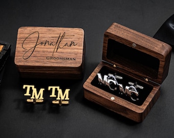 May include: A wooden box with a hinged lid, engraved with the name "Jonathan" and the word "Groomsman". The box contains a pair of silver cufflinks with the initials "TM" engraved on them.