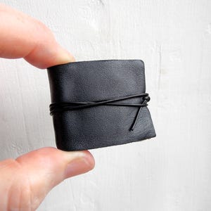 May include: A small black leather journal with a black cord tied around it.