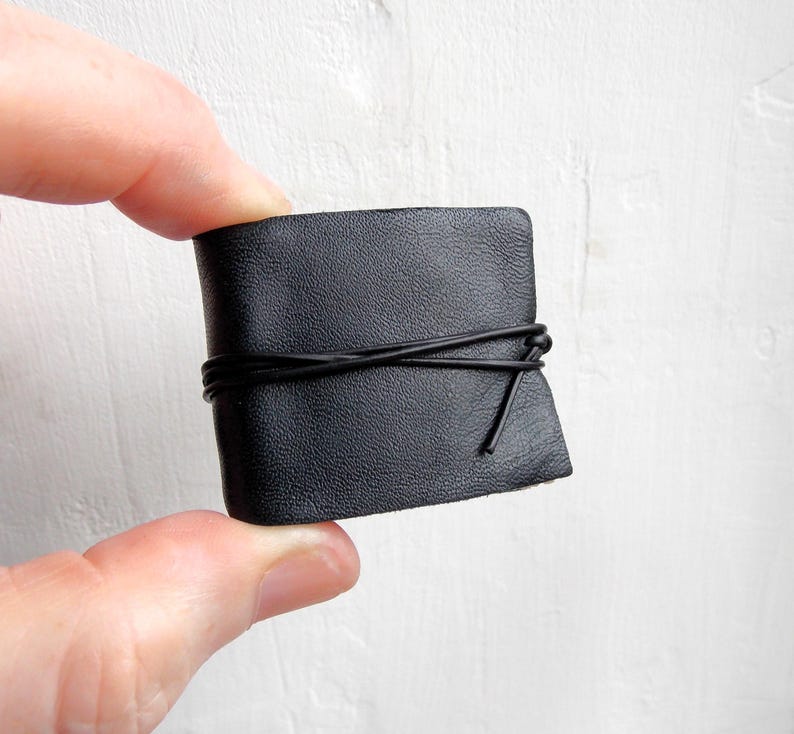 May include: A small black leather journal with a black cord tied around it.