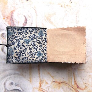 May include: A small, handmade notebook with a blue and white floral patterned cover and a blank, brown paper interior.