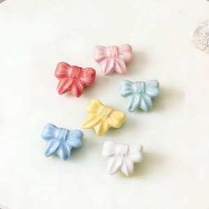 Tiradores de cerámica con forma de lazo, tiradores para armarios infantiles, tiradores de cajones con dibujos animados, tiradores para puertas de armarios, herrajes para muebles de tocador.