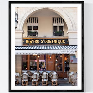 May include: A Parisian bistro with a black and white striped awning, a sign that reads "Bistro St Dominique", and a cafe sign that reads "Cafe Restaurateur". The bistro has a large window with a sign that reads "Cocktails", and there are tables and chairs set up outside.